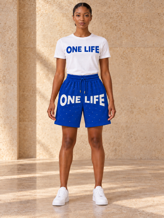Women's Blue Magic blue shorts with a white One Life shirt featuring a royal blue logo, front view.