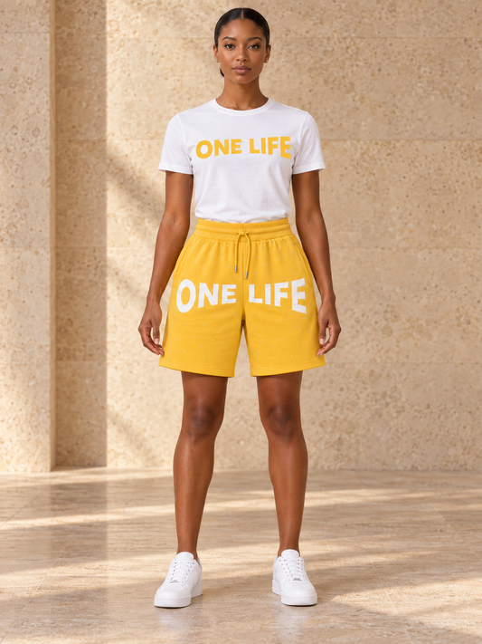 Women's Lemon Pepper yellow shorts with a white One Life shirt featuring a golden yellow logo, front view.